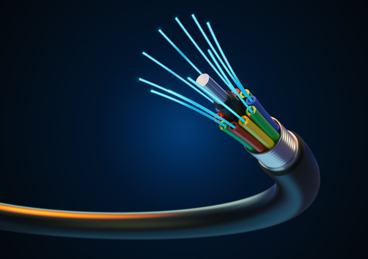 The cut end of a black fibre optic cable, its coloured fibres spread out and the glass strands glowing blue